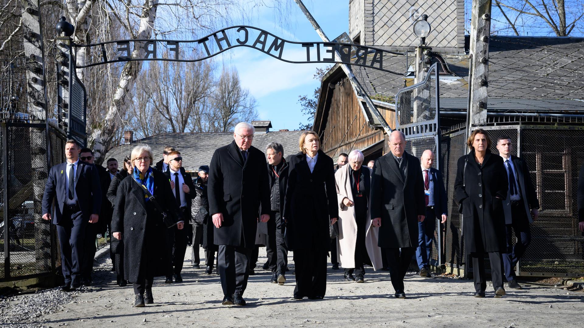 Bundespräsident Steinmeier (4.v.r.) und seine Frau Elke Büdenbender (3.v.r.) gehen zusammen mit Bundeskanzler Scholz (2.v.r., SPD) und seiner Frau Britta Ernst (r) durch das Tor des ehemaligen deutschen Konzentrations- und Vernichtungslager Auschwitz-Birkenau.