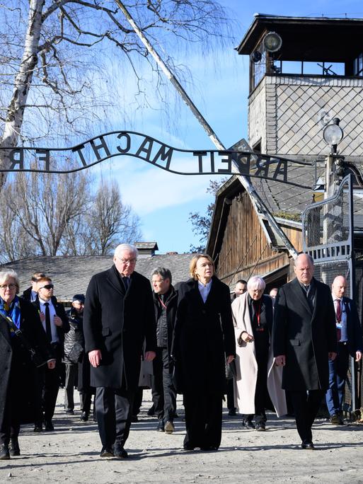 Polen, Oswiecim: Bundespräsident Steinmeier (4.v.r.) und seine Frau Elke Büdenbender (3.v.r.)  gehen zusammen mit Bundeskanzler Scholz (2.v.r., SPD) und seiner Frau Britta Ernst (r) durch das Tor des ehemaligen deutschen Konzentrations- und Vernichtungslager Auschwitz-Birkenau, Stammlager Auschwitz I, mit dem Schriftzug "Arbeit macht frei".