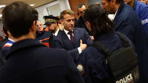 Der französische Präsident Emmanuel Macron steht im Rathaus von Trappes in einer Gruppe von Polizeibeamten und Rettungskräften