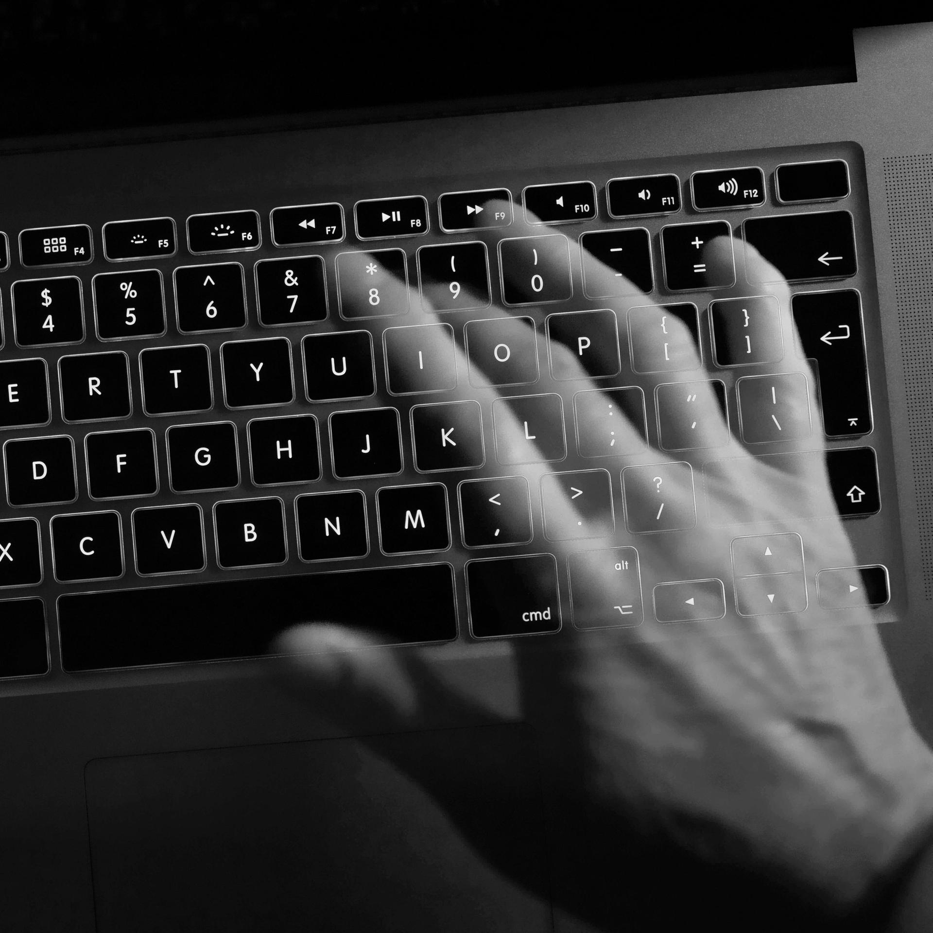 Eine Hand schreibt auf einer Computertastatur.