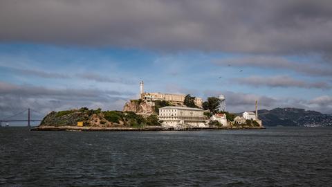 Wir sehen das Gefängnis Alcatraz, das auf einer Insel umgeben von Wasser in der Bucht von San Francisco liegt. 