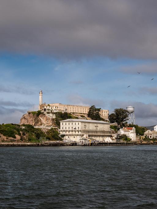 Wir sehen das Gefängnis Alcatraz, das auf einer Insel umgeben von Wasser in der Bucht von San Francisco liegt. 