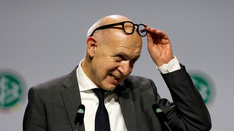 Neuendorf steht auf der Bühne beim DFB-Bundestag und schiebt seine Brille auf die Stirn.
