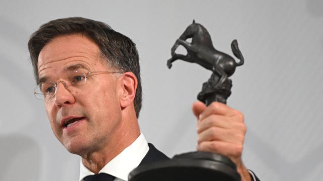 Das Foto zeigt NATO-General-Sekretär Rutte. Er hält den Friedens-Preis in der Hand. Der Preis ist eine Pferde-Skulptur aus Eisen.