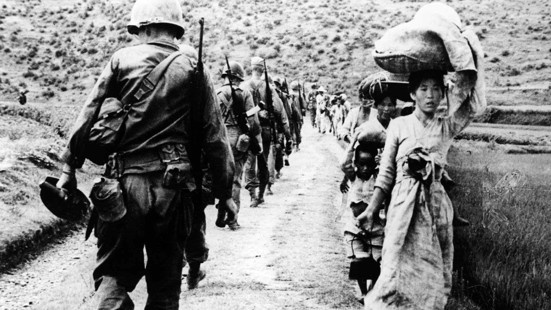 Südkoreaner fliehen im August 1950 aus dem Kampfgebiet während US-Soldaten als Verstärkung zur Front marschieren. Südkoreaner fliehen im August 1950 aus dem Kampfgebiet während US-Soldaten als Verstärkung zur Front marschieren.