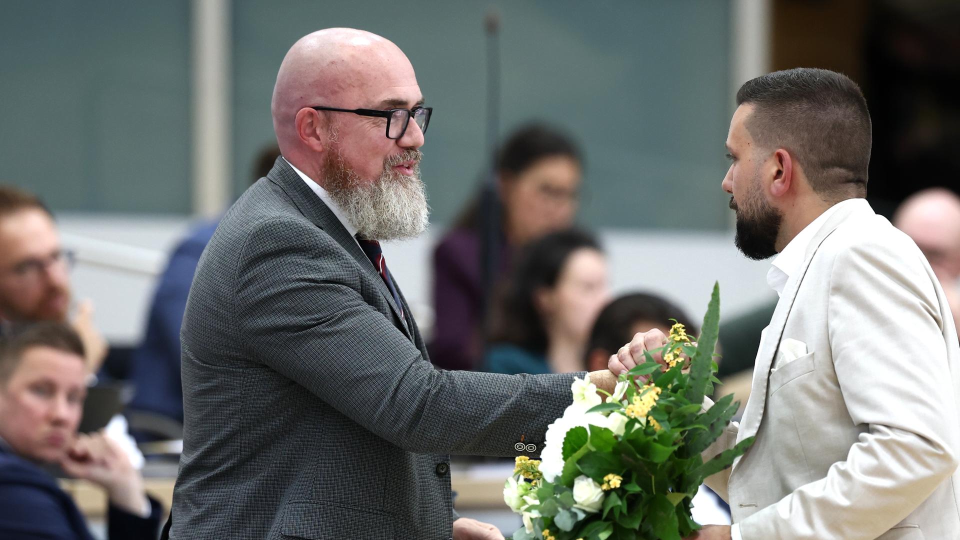 Tobias Rausch (r, AfD) gratuliert Hans-Thomas Tillschneider (AfD) zu dessen Wahl zum stellvertretenden Landtagspräsidenten während der konstituierenden Sitzung des Landtags in Sachsen-Anhalt. Rausch hält Blumen in der Hand.