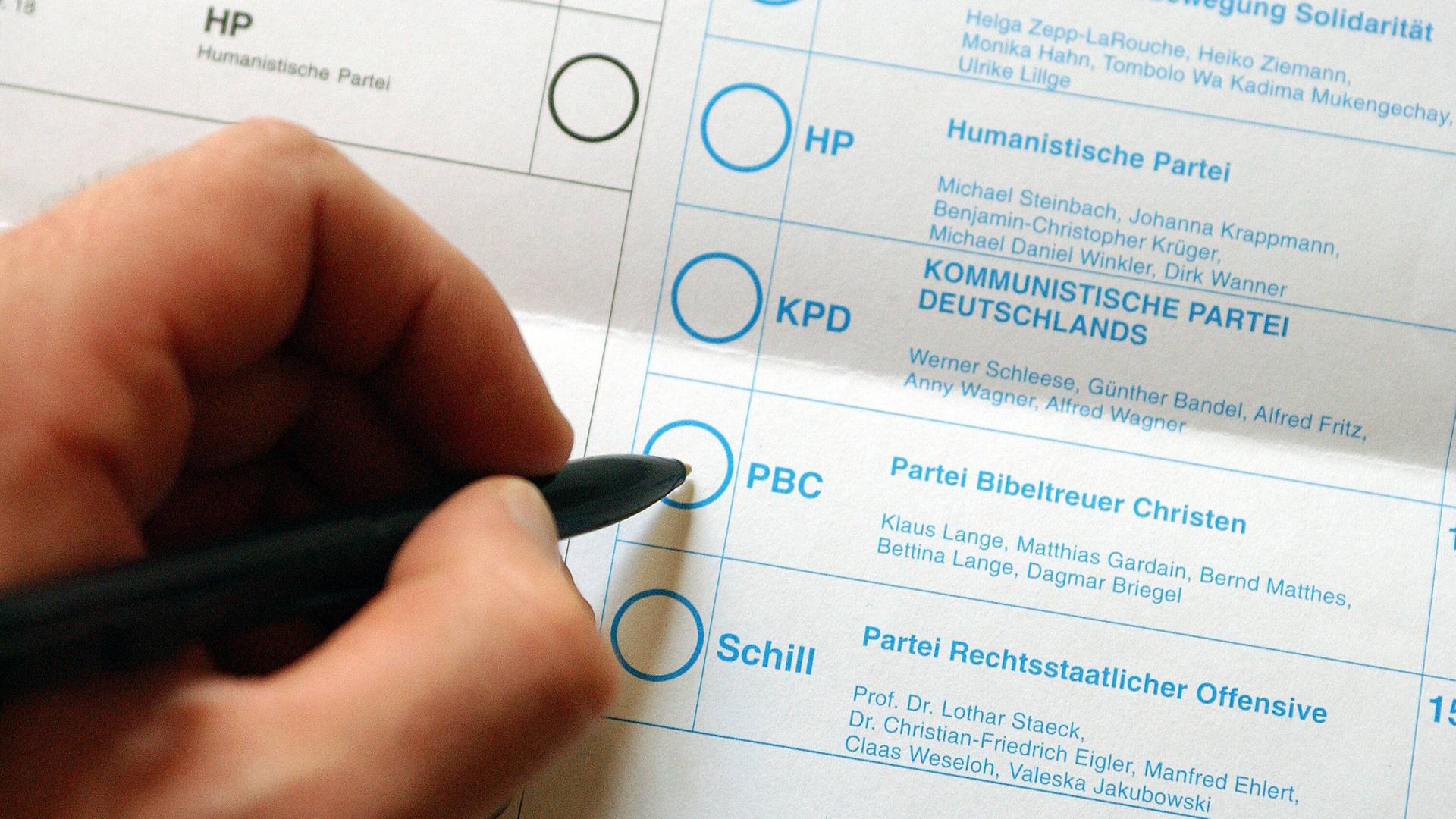 Stimmzettel zur Wahl des Deutschen Bundestages am 22. September 2002. Eine Hand ist kurz davor der Partei Bibeltreuer Christen zu geben. Weitere Parteien des Stimmzettels sind Schill Partei, Humanistische Partei