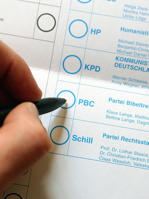 Stimmzettel zur Wahl des Deutschen Bundestages am 22. September 2002. Eine Hand ist kurz davor der Partei Bibeltreuer Christen zu geben. Weitere Parteien des Stimmzettels sind Schill Partei, Humanistische Partei
