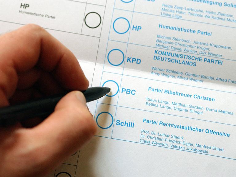 Stimmzettel zur Wahl des Deutschen Bundestages am 22. September 2002. Eine Hand ist kurz davor der Partei Bibeltreuer Christen zu geben. Weitere Parteien des Stimmzettels sind Schill Partei, Humanistische Partei