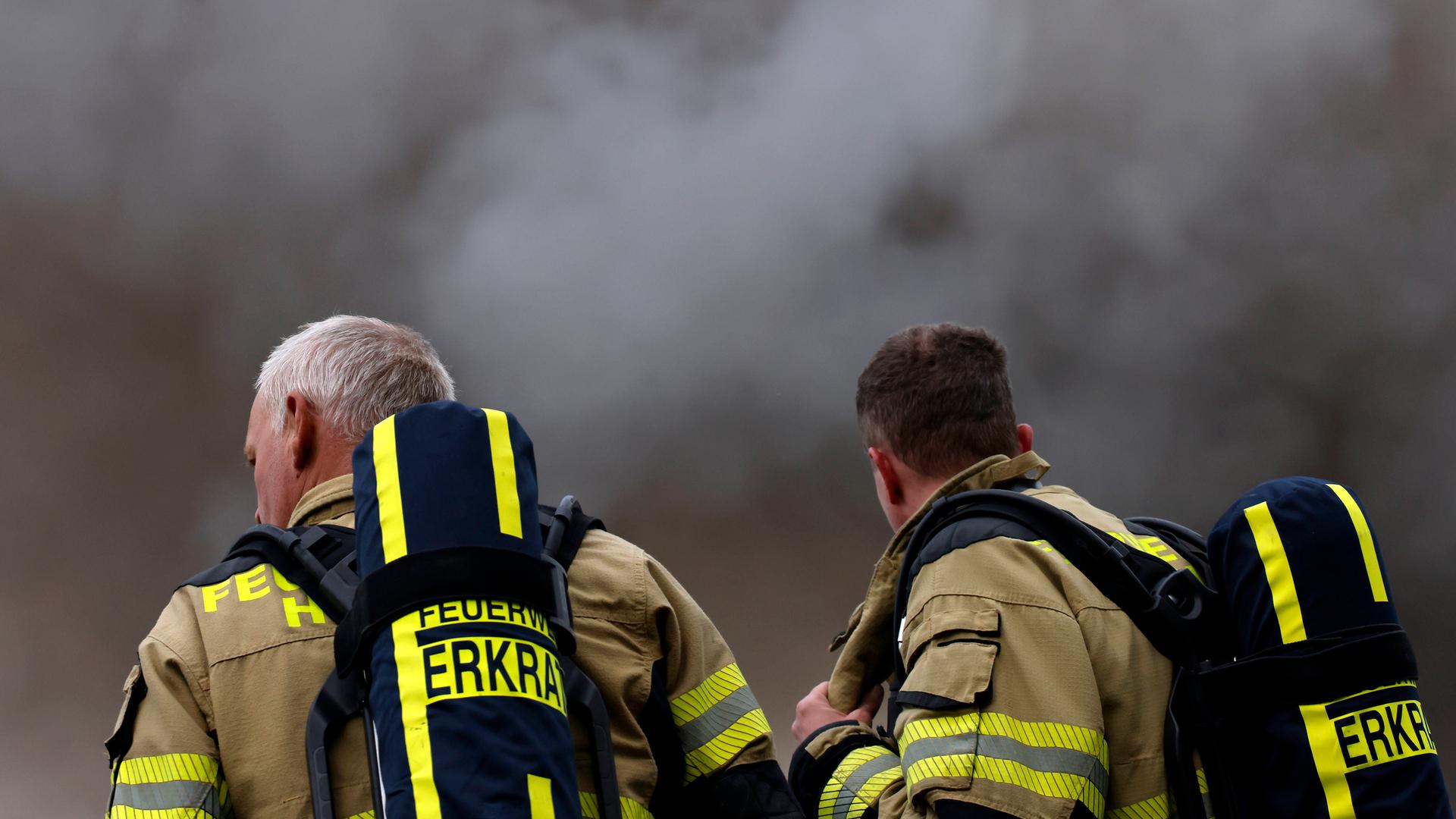Eine große Rauchwolke - davor zwei Feuerwehrleute. Eine große Rauchwolke - davor zwei Feuerwehrleute.