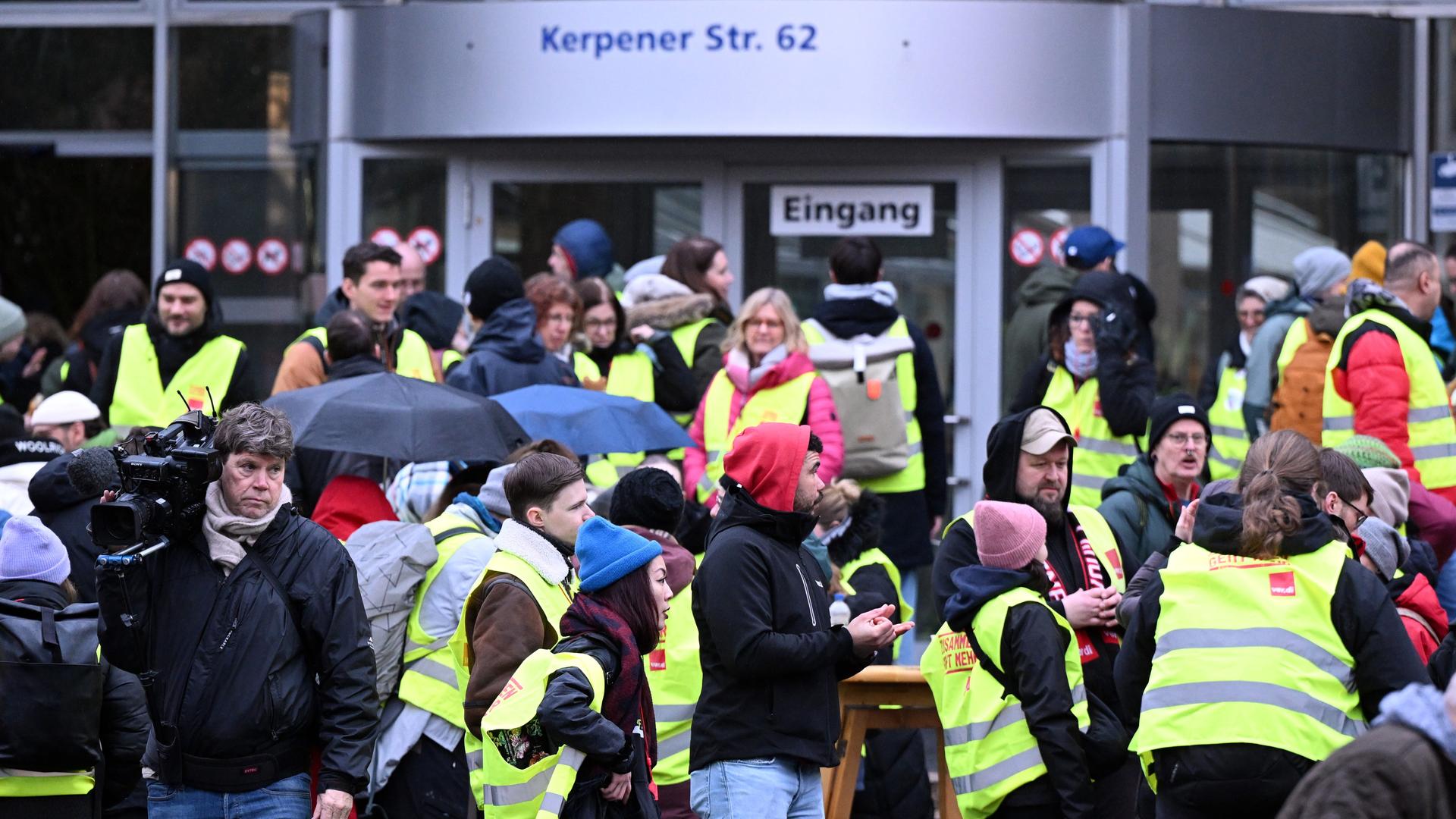 Beschäftigte der Uniklinik Köln stehen bei einen Warnstreik vor dem Haupteingang. 