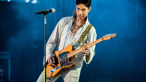 Prince Rogers Nelson mit E-Gitarre auf der Bühne (2011 in England)