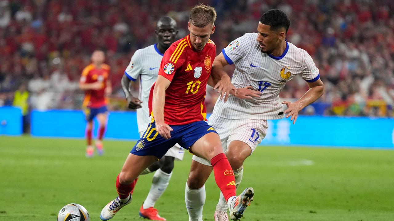 Der spanische Fußballnationalspieler Dani Olmo kämpft während des Halbfinalspiels zwischen Spanien und Frankreich bei der Fußball-Europameisterschaft 2024 in München mit dem Franzosen William Saliba um den Ball.