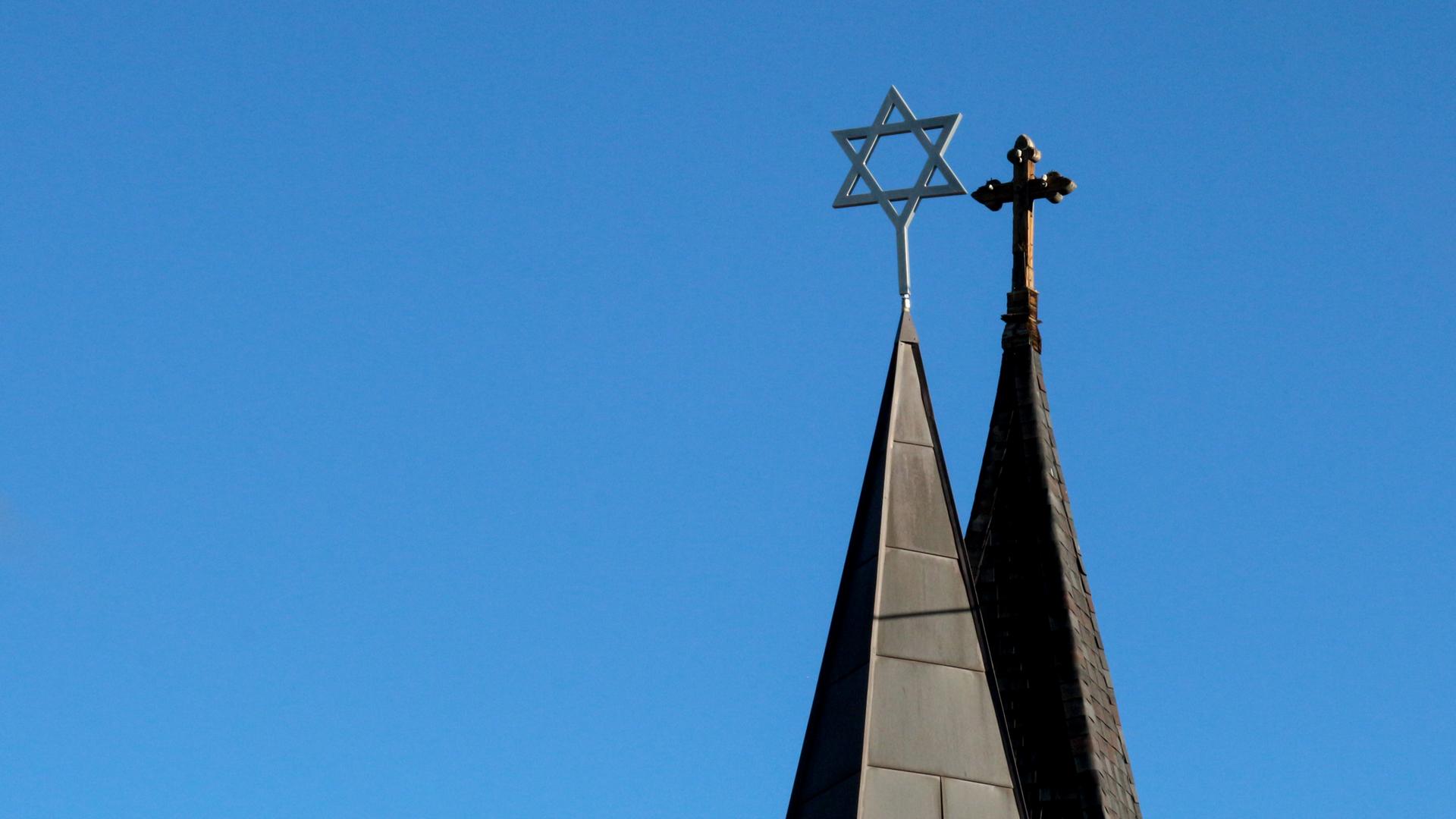 Blick auf die Türme einer Synagoge mit Davidstern und eine Kirche mit Kreuz Blick auf die Türme einer Synagoge mit Davidstern und eine Kirche mit Kreuz