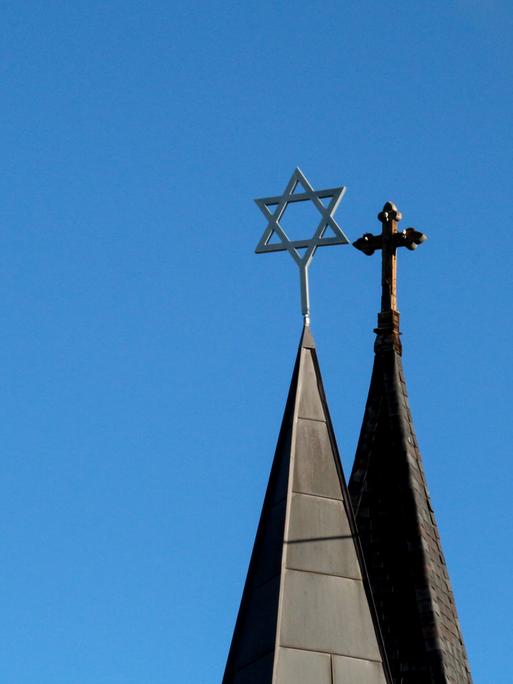 Blick auf die Türme einer Synagoge mit Davidstern und eine Kirche mit Kreuz