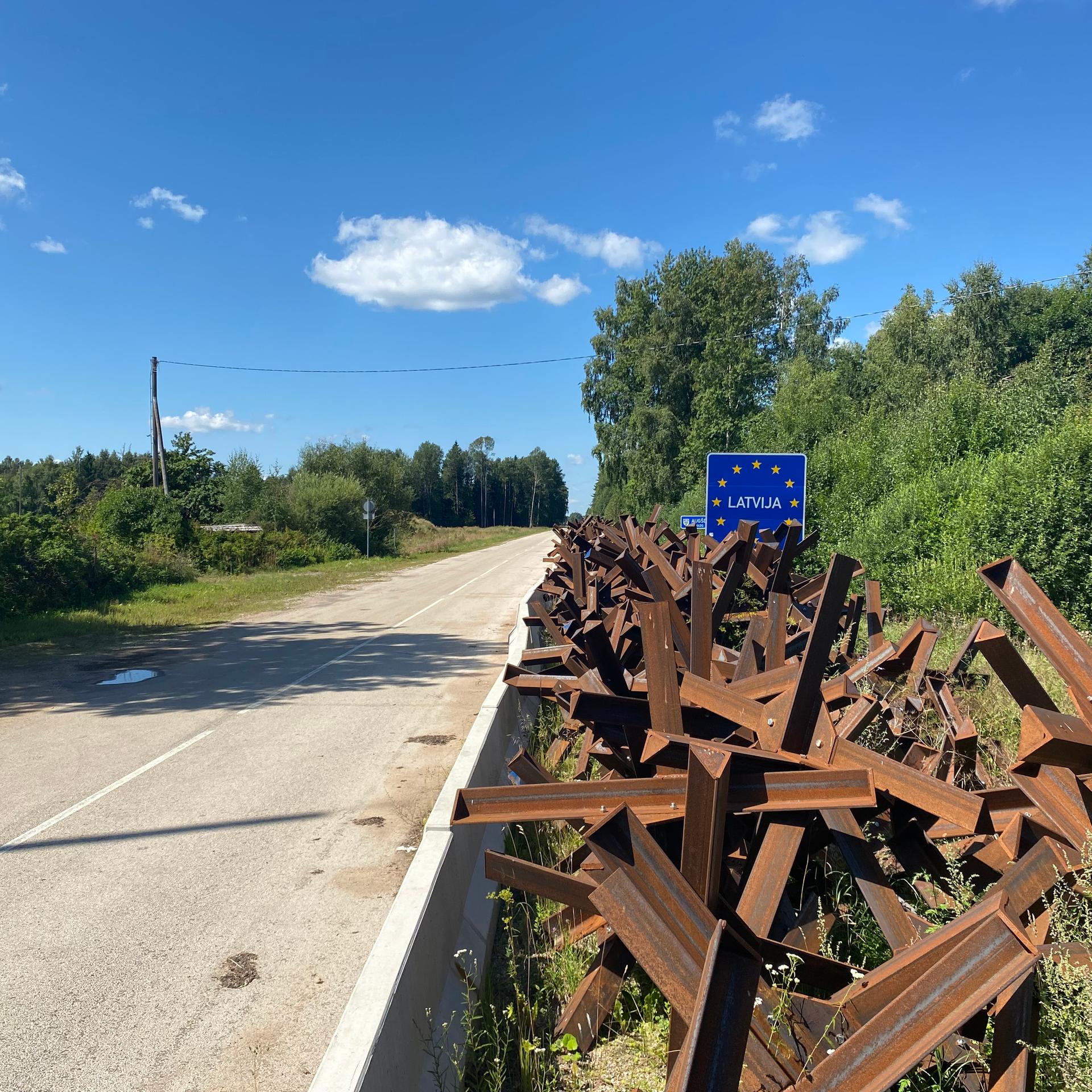 Ein Schild mit der Aufschrift "Latvijas" und Panzersperren stehen an der Grenze zu Belarus.