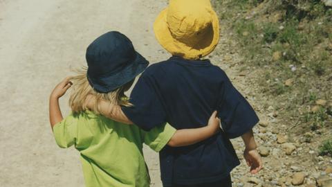 Ein altes Kinderfoto von Vanessa und Philipp, sie laufen Arm in Arm einen Waldweg entlang.