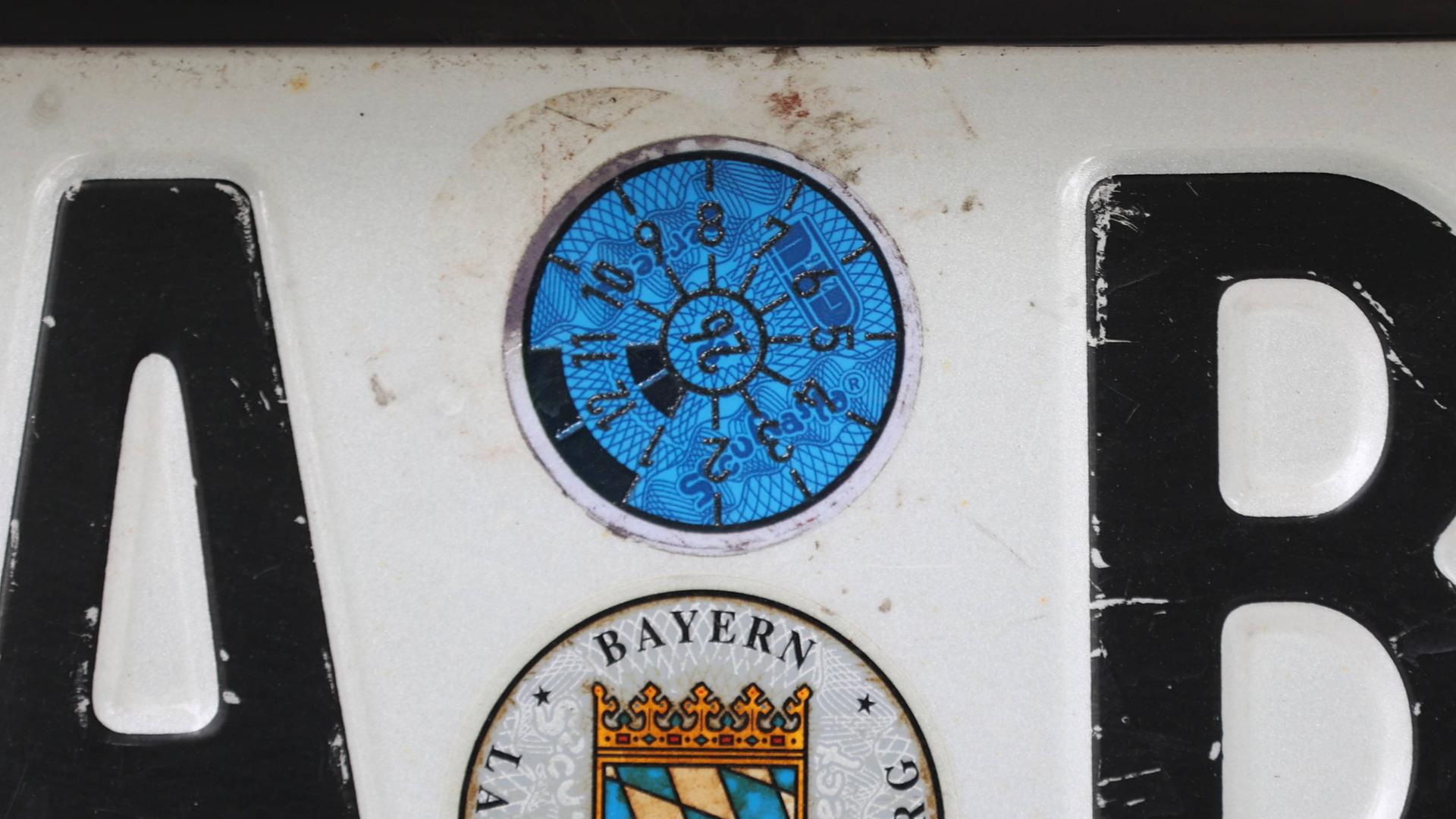 Eine TÜV- Plakette auf einem PKW-Nummerschild Eine TÜV- Plakette auf einem PKW-Nummerschild