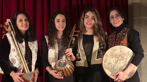 Vier Frauen stehen mit drei iranischen, traditionellen Instrumenten und lachen in die Kamera.
