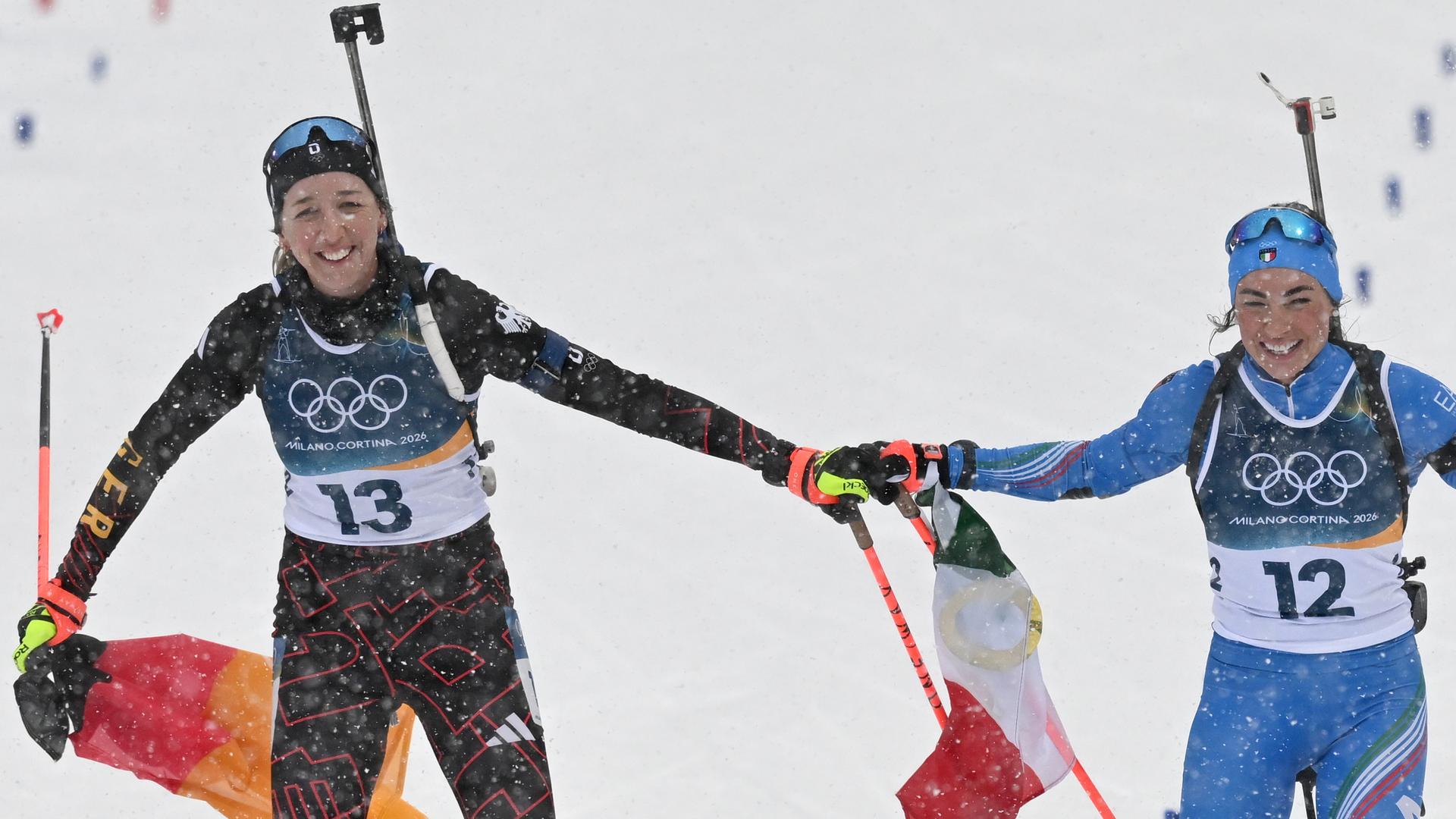 Das Foto zeigt die deutsche Biathletin Franziska Preuß (links) und Dorothea Wierer aus Italien. Sie kommen jubelnd ins Ziel.