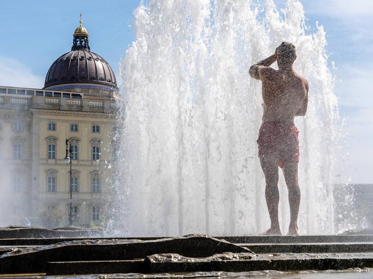 Bei Temperaturen von über 30 Grad erfrischt sich ein Mann in Badehose im Lustgarten unter der Fontäne, Berlin, 11. Juli 2023, 