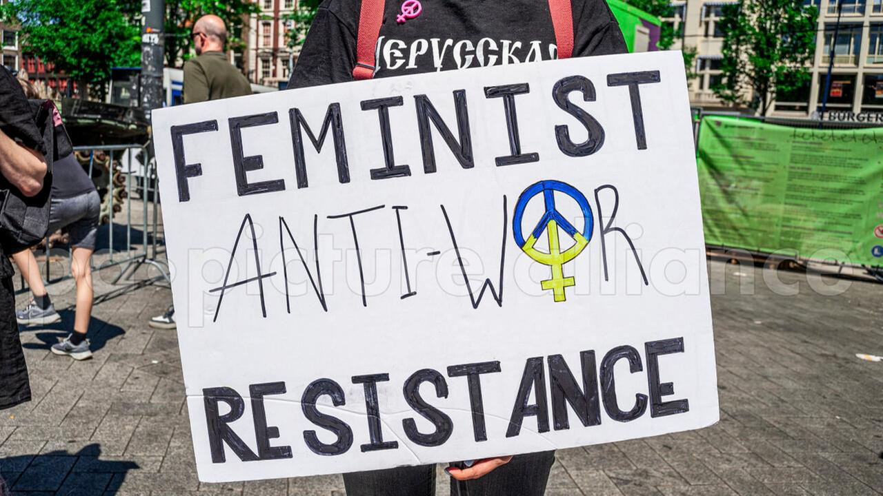 Eine Demonstrantin zeigt ein Plakat, auf dem die Worte "Feminist Anti-War Resistance" stehen. Eine Demonstrantin zeigt ein Plakat, auf dem die Worte "Feminist Anti-War Resistance" stehen.