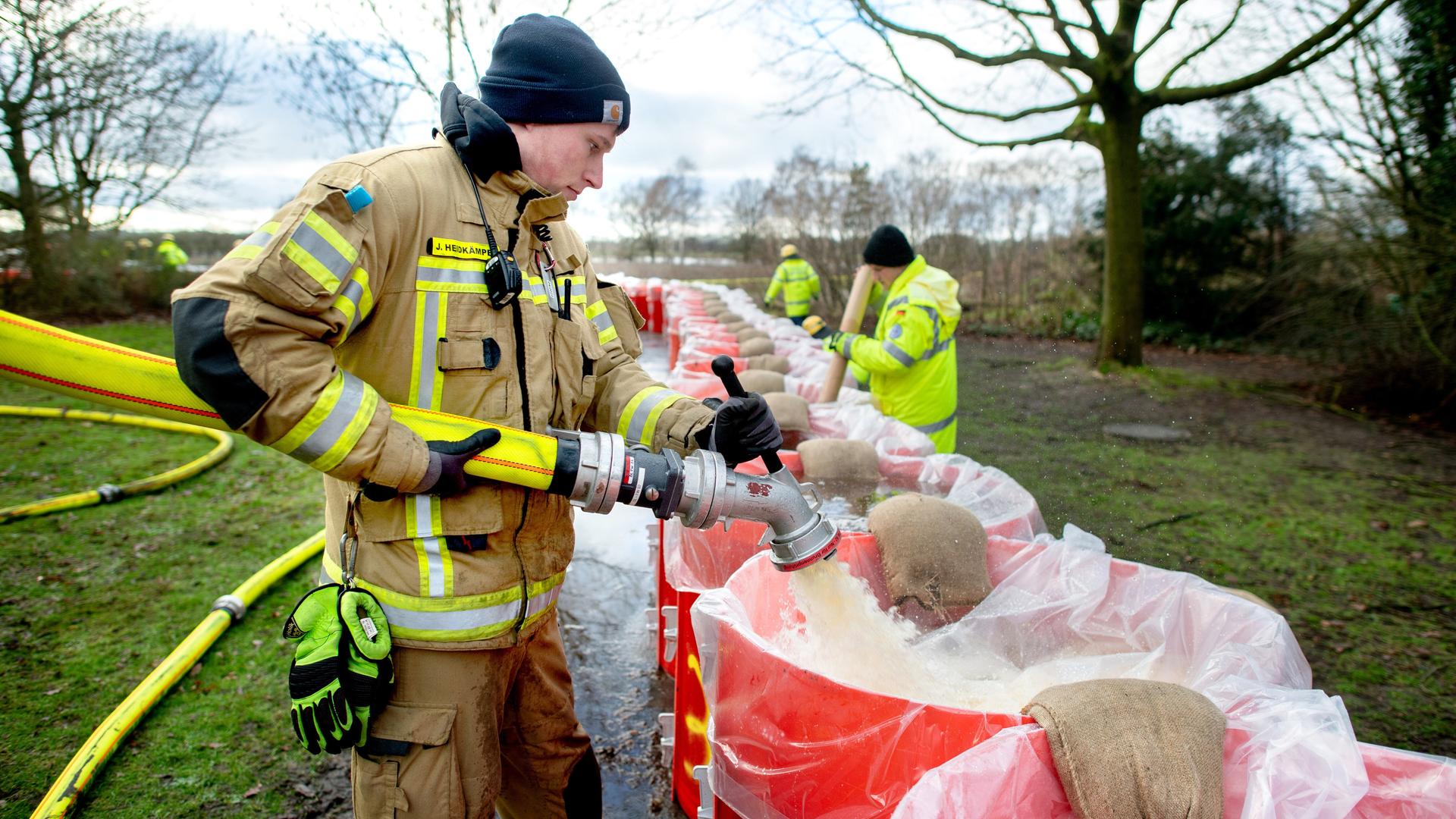 Ein Feuerwehrmann befüllt eine große rote Tonne mit Wasser.