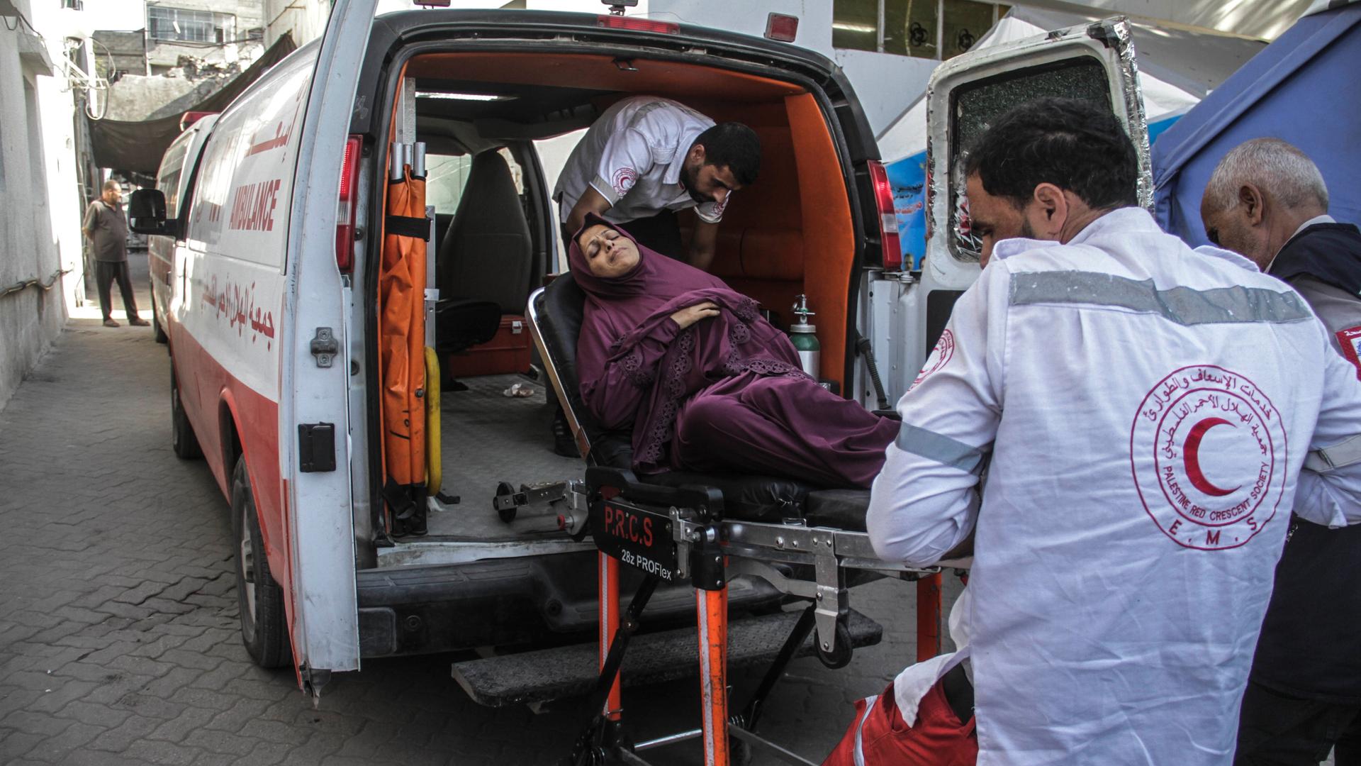 Ersthelfer laden eine verletzte Frau auf einer Bahre in einen Krankenwagen ein.