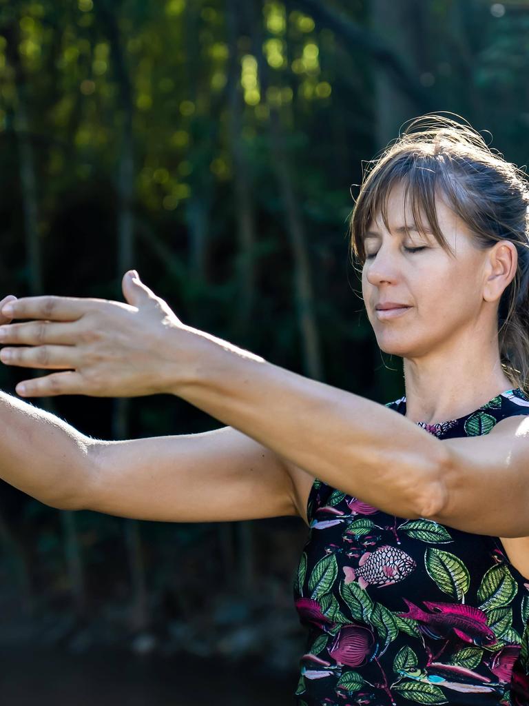 Qigong Meisterin beim üben der chinesischen Kampfkunst in der Natur. Sonnenlicht erhellt die Szene 