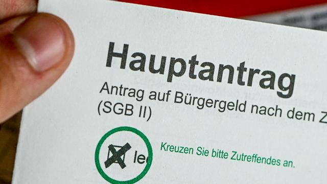 Im Jobcenter Berlin Treptow-Köpenick hält ein Mann einen Antrag auf Bürgergeld in der Hand. 