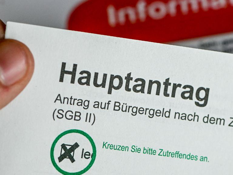 Im Jobcenter Berlin Treptow-Köpenick hält ein Mann einen Antrag auf Bürgergeld in der Hand. 