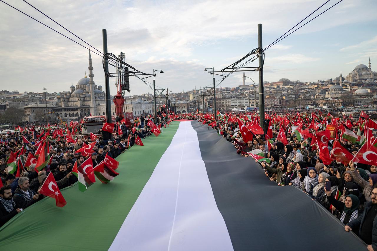 Tausende demonstrieren auf der Galata-Brücke in Istanbul mit einer riesigen palästinensischen Flagge. 
