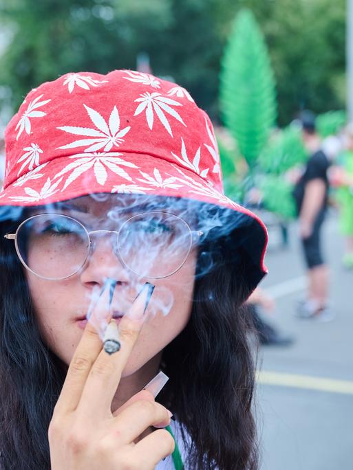 Die Teilnehmerin einer Demonstration für die Cannabis-Legalisierung raucht einen Joint auf der Hanfparade, die laut Angaben der Veranstalter die größte Demonstration für Cannabis in Deutschland ist