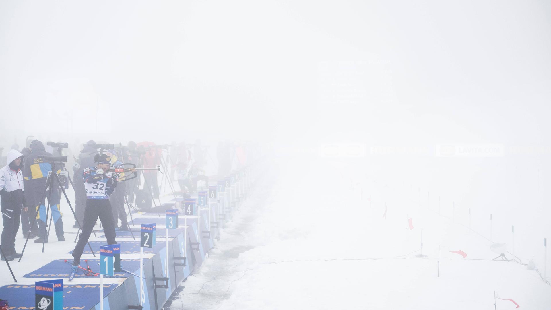 Athletinnen und Trainer stehen an einem Biathlon-Schießstand beim Weltcup in Oslo, der in dichten Nebel gehüllt ist.