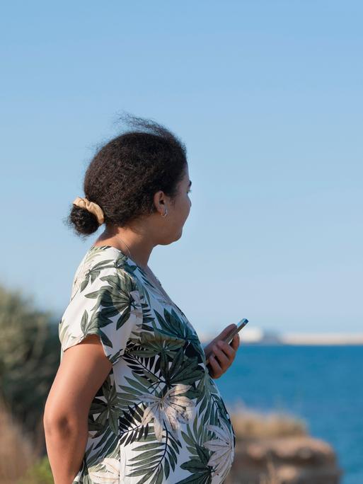 Seitenansicht einer schwangeren Frau am Meer. (Symbolfoto)