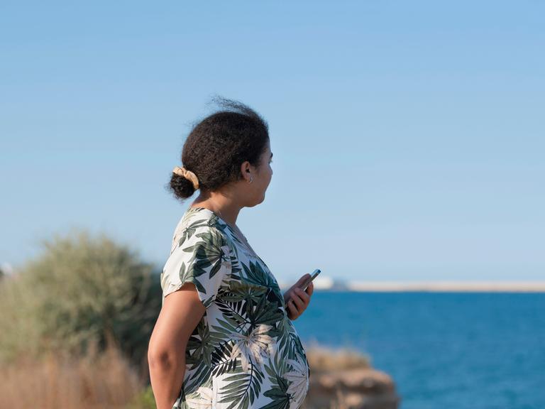 Seitenansicht einer schwangeren Frau am Meer. (Symbolfoto)