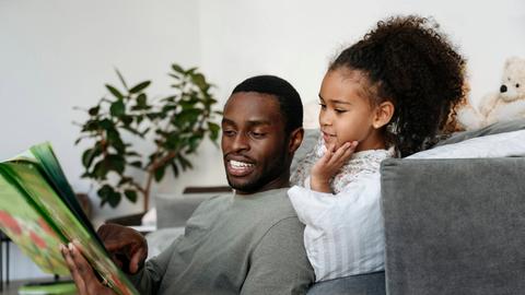 Young man telling story to daughter in living room model released property released, VYF00604