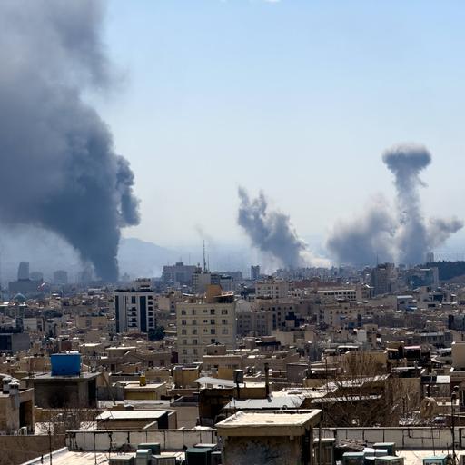 Über sehr vielen Häusern sind mehrere große Rauchwolken zu sehen, die in den Himmel aufsteigen.