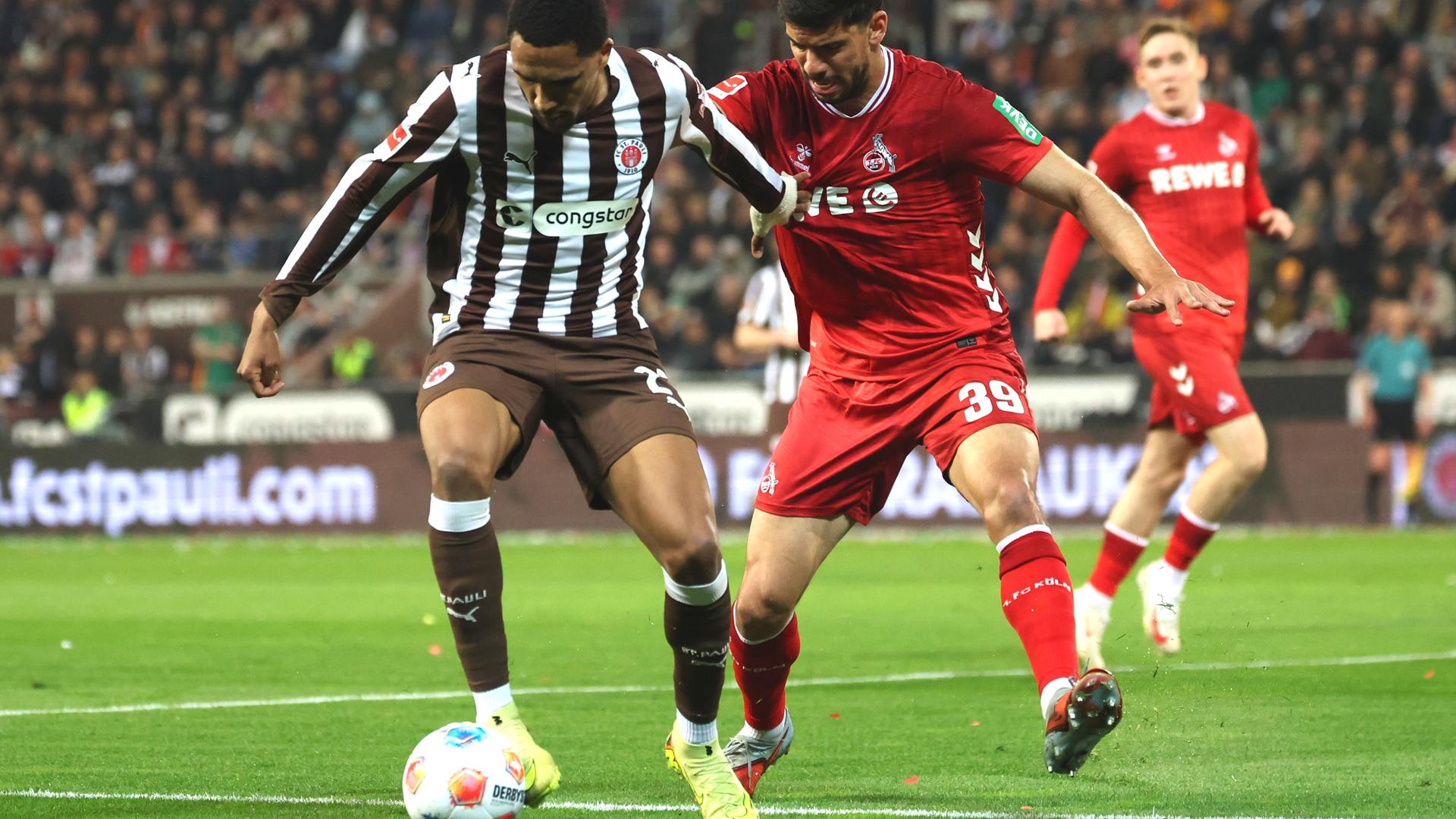 Die Fußballspieler Andréas Hountondji von St. Pauli und Cenk Özkaçar vom 1. FC Köln