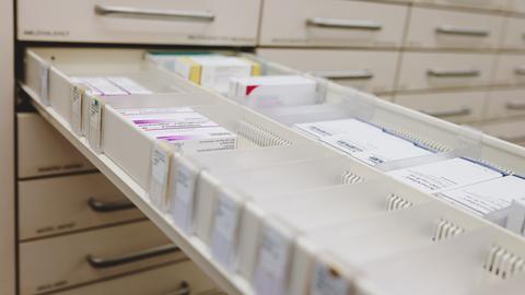 In einem geöffneten Arzneimittelschrank in einer Apotheke sind mehrere Packungen Medikamente sortiert.