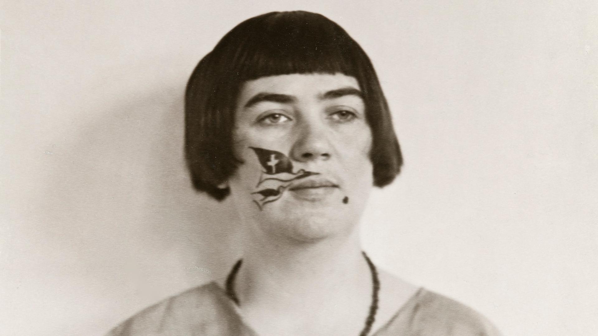 Schwarz-Weiß-Fotografie der Kölner Dadaistin Marta Hegemann mit Pagenschnitt und einer Zeichnung im Gesicht.