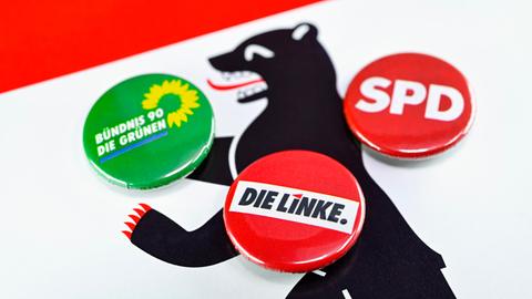 Parteianstecker von Die Linke, SPD und Die Grünen auf dem Wappen von Berlin