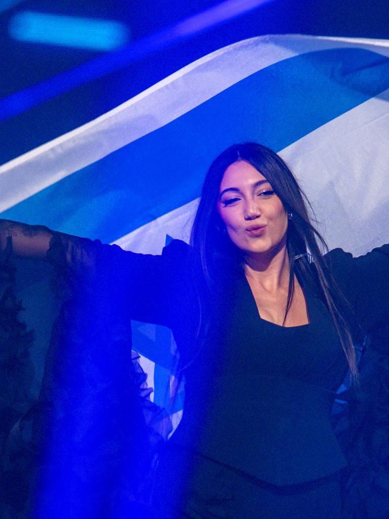 Die israelische ESC-Kandidatin Yuval Raphael steht auf einer Bühne und schwenkt eine israelische Fahne hinter ihrem Rücken.