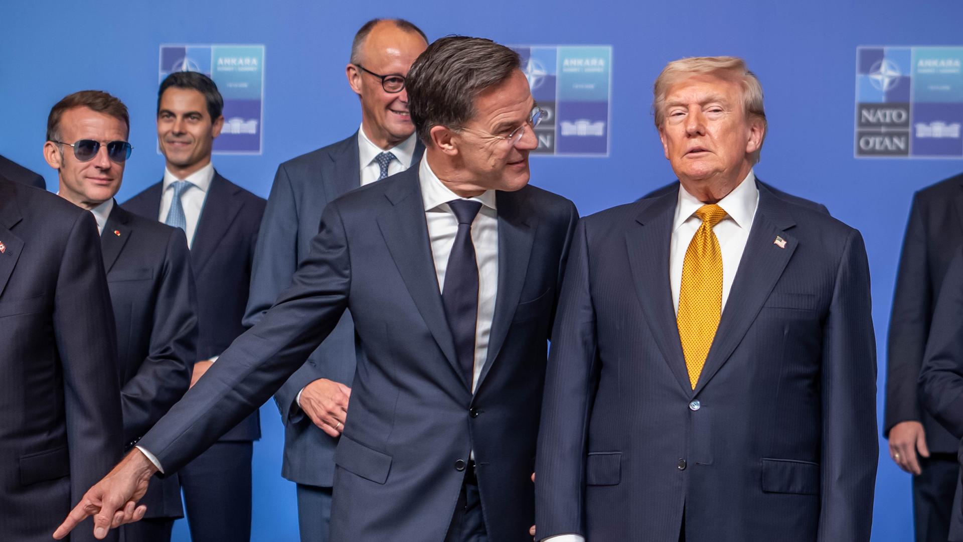 US-Präsident Donald Trump steht neben Nato-Generalsekretär Mark Rutte und vor Bundeskanzler Friedrich Merz und Frankreichs Präsidenten Emmanuel Macron beim Nato-Gipfel in Ankara US-Präsident Donald Trump steht neben Nato-Generalsekretär Mark Rutte und vor Bundeskanzler Friedrich Merz und Frankreichs Präsidenten Emmanuel Macron beim Nato-Gipfel in Ankara
