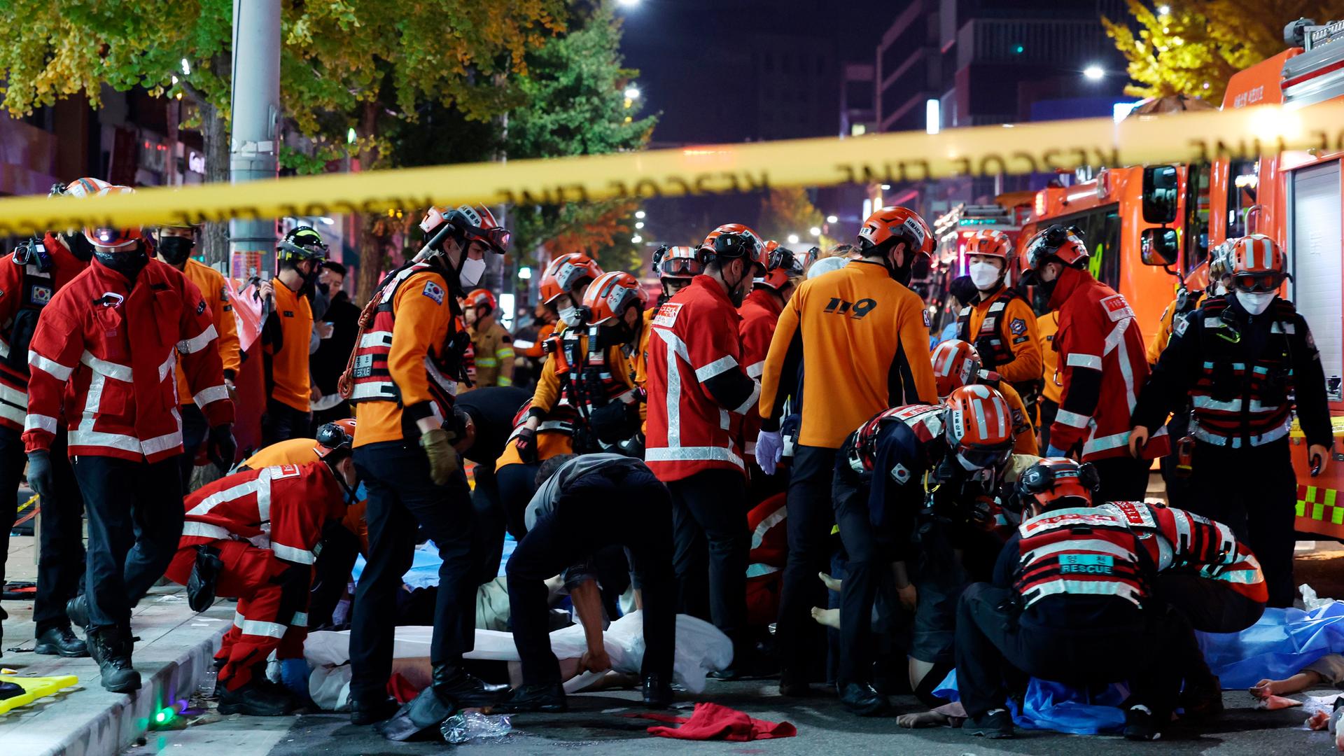Auf dem Bild sind zahlreiche Rettungs-Kräfte mit Helmen und roten Jacken zu sehen.  Im Vordergrund ist ein gelbes Flatter-Band von der Polizei.