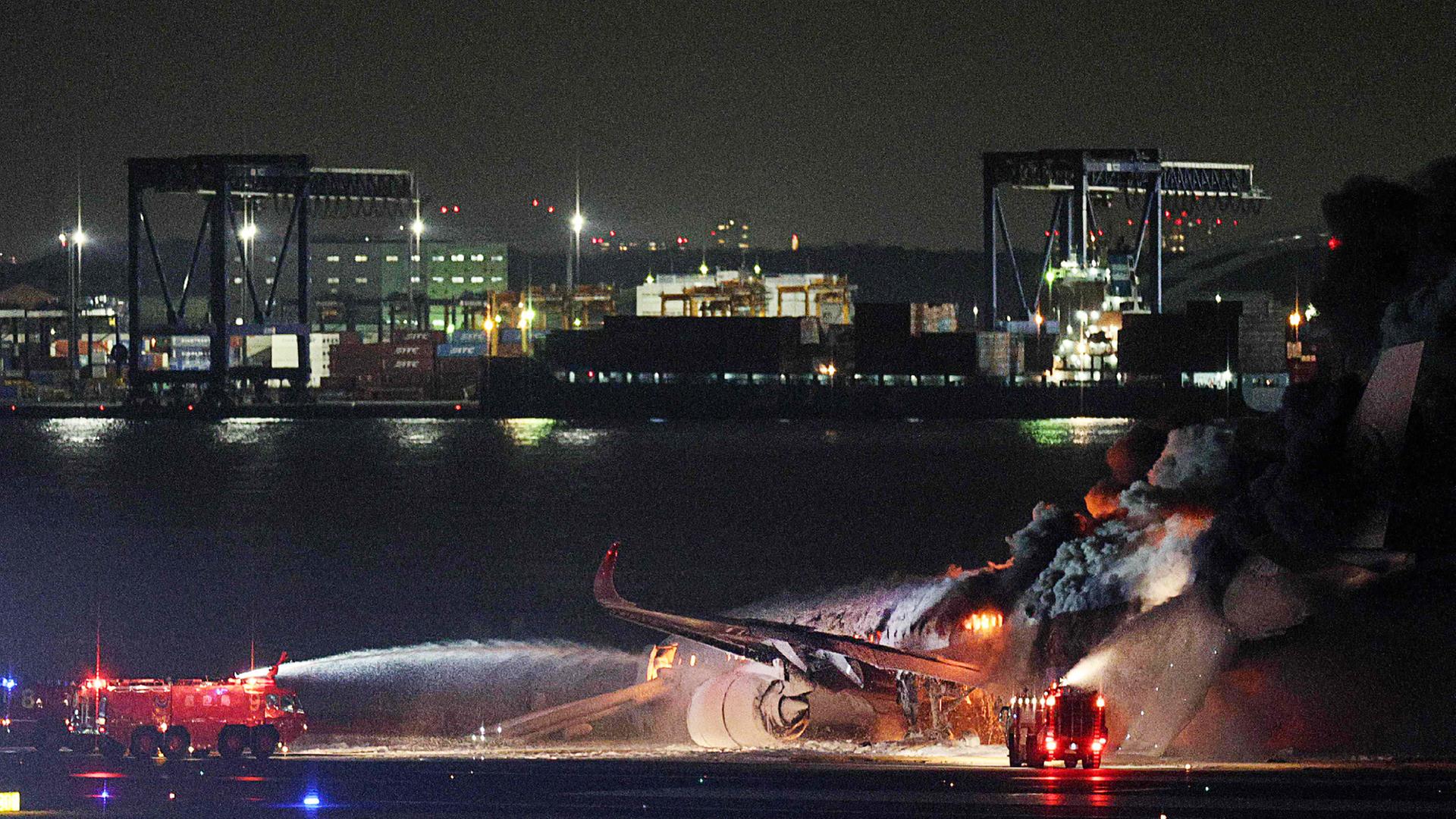 Feuerwehrmänner versuchen, das auf dem Flughafen Haneda in Tokio in Brand geratene Flugzeug zu löschen. Feuerwehrmänner versuchen, das auf dem Flughafen Haneda in Tokio in Brand geratene Flugzeug zu löschen.