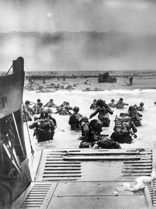 Eine historisches Aufnahme des D-Day am 6. Juni 1944. Alliierte Einheiten landen an der französischen Atlantikküste in der Normandie in Frankreich während des 2. Weltkriegs. Soldaten am Strand, die aus einem Militärschiff steigen.