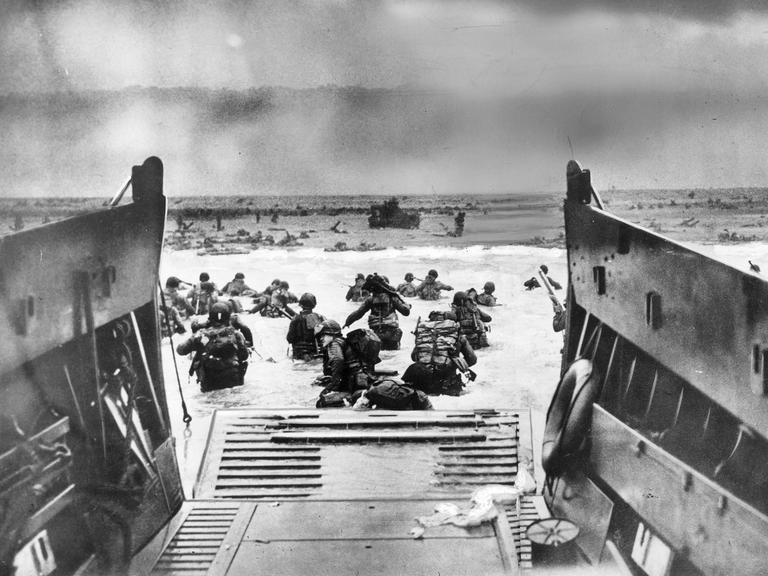 Eine historisches Aufnahme des D-Day am 6. Juni 1944. Alliierte Einheiten landen an der französischen Atlantikküste in der Normandie in Frankreich während des 2. Weltkriegs. Soldaten am Strand, die aus einem Militärschiff steigen.
