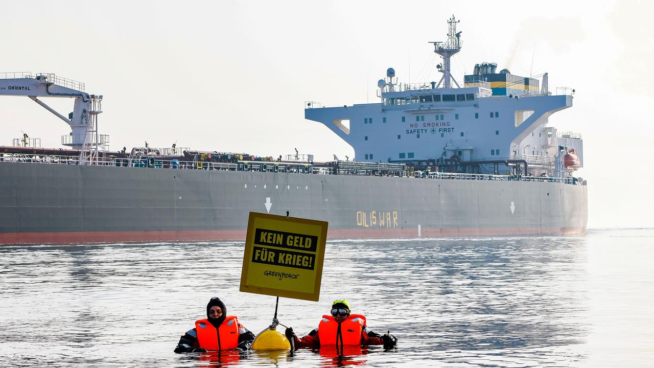 Aktivisten der Umweltorganisation Greenpeace demonstrieren in der Ostsee vor einem Schiff, das russisches Öl transportiert. Auf einem Plakat steht: Kein Geld für Krieg. 