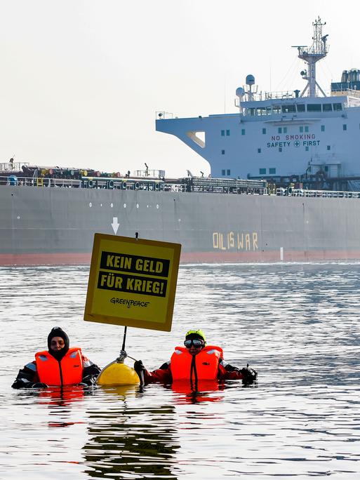 Aktivisten der Umweltorganisation Greenpeace demonstrieren in der Ostsee vor einem Schiff, das russisches Öl transportiert. Auf einem Plakat steht: Kein Geld für Krieg. 